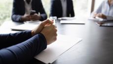 Ihmisiä kerääntynyt pöydän ympärille neuvotteluun