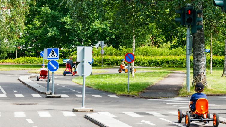 Lapsi lähestyy punaisia liikennevaloja liikennepuistossa. Kuva: Mostphotos.